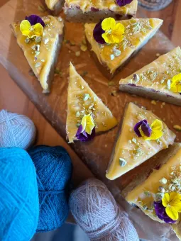 Bakverk dekorerade med en blomma, brevid ligger garnnystan.