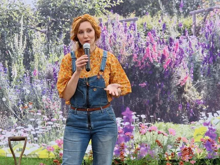 En person som står framför en blomsterträdgård.