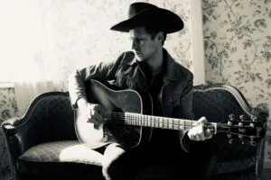 En person med cowboy-hatt som spelar gitarr.