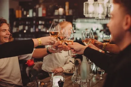 Män och kvinnor vid ett bord som skålar med vinglas.