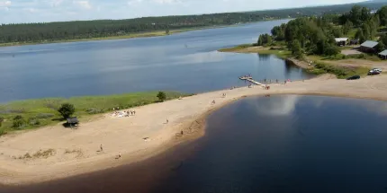 Badudde omgiven av träd, gräsmatta och liten brygga
