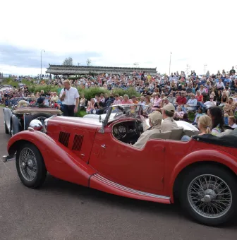 Äldre bil och många åskådare. 