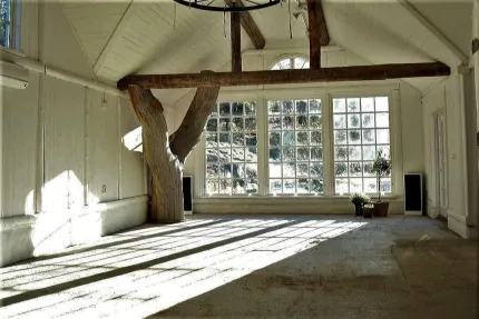 Ett rum med vita väggar, högt i tak, ett stort fönster  med små glasrutor på ena kortsidan.