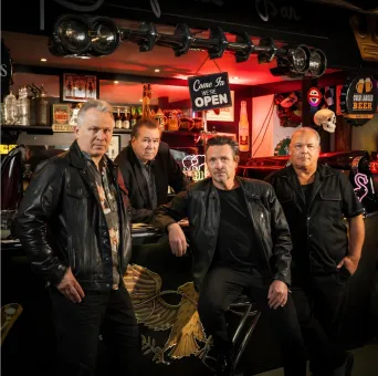 Fyra män iklädda svarta kläder som står i en bar.