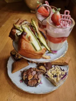 Ett vitt porslinsfat i två våningar, på fatet diverse bakverk och två glas med smoothies.