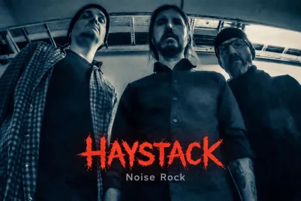 Tre personer står inomhus i ett fordon, sedda underifrån, med röd text “HAYSTACK” och “Noise Rock” nedtill..