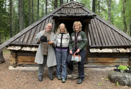 Tre kvinnor framför en skogssamekåta, skog i bakgrunden.
