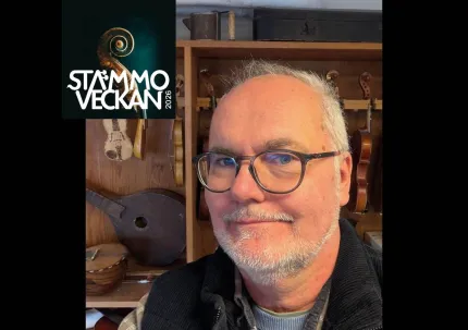 En man i glasögon och skägg, stämmoveckan med vita bokstäver, instrument i bakgrunden.