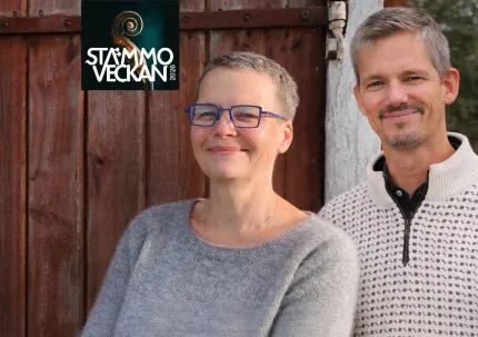 En kvinna med kort hår och glasögon iklädd en grå stickad tröja, en man i kort hår iklädd en vit stickad tröja med små svarta mönster, en röd trävägg i bakgrunden, logga Stämmoveckan.