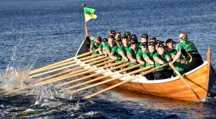 Kyrkbåtsroddare i gröna tröjor som tar i.