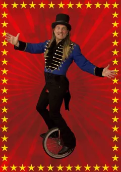 En man i långt hår iklädd svarta byxor, blå rock med guld emblem och svart hög hatt, han cyklar på en enhjuling, röd bakgrund med en ram av guldstjärnor.