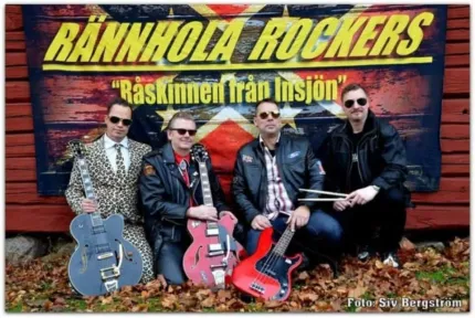 Fyra män i solglasögon, tre av dem håller i en gitarr den fjärde håller i ett par trumpinnar, banderoll Rännhola rockers i bakgrunden.