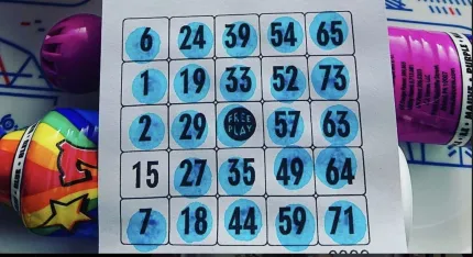 Närbild av en bingobricka där flera rutor är markerade med blått, med färgglada markörer runtom..