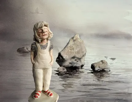 Handgjord figur av ett barn i vit hätta och overall står vid en dimmig strand med stenar i vattnet..