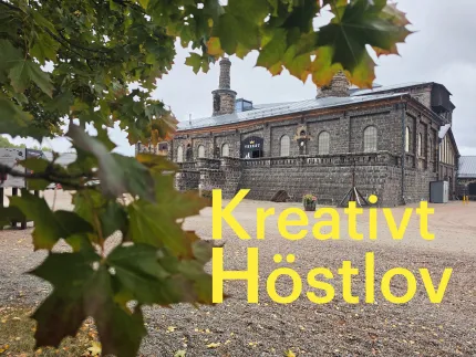 Gula texten "Kreativt Höstlov" framför en äldre industribyggnad i tegel, inramad av löv i förgrunden..