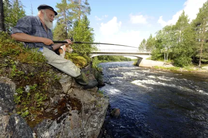 Fiskare sitter på klippa och fiskar ut i älven