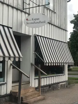 Entré till ett vitt hus med markis som hänger ner över husets fönster. 