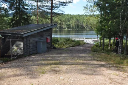 Vindskydd ner mot vattnet där brygga sticker ut i vattnet i änden på väg som går ända ner till vattnet.