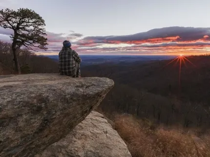 Man som sitter på en klipphäll med utsikt.