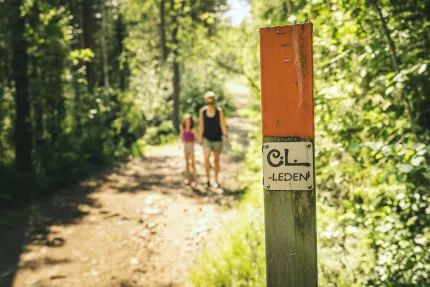 Orange ledmarkering, vandrande kvinna och barn i bildens bakgrund.