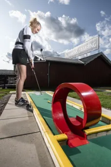 Girl standing by the track with club in hand.