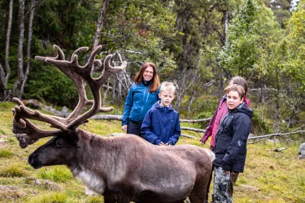 Två kvinnor och två barn står tillsammans med en ren.