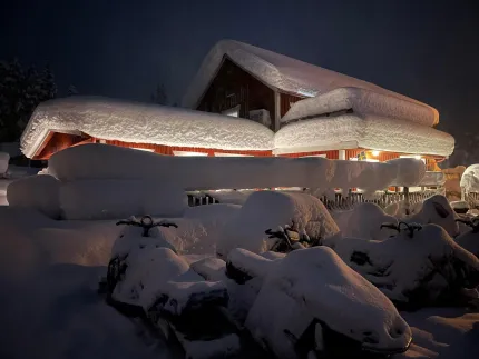 Rött hus med mycket snö på taket.