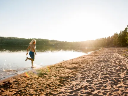 Ett barn som springer i vattnet på en sandstrand i solnedgången.