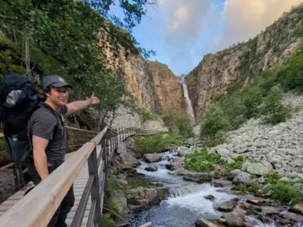 En person som står på en bro nära ett vattenfall.