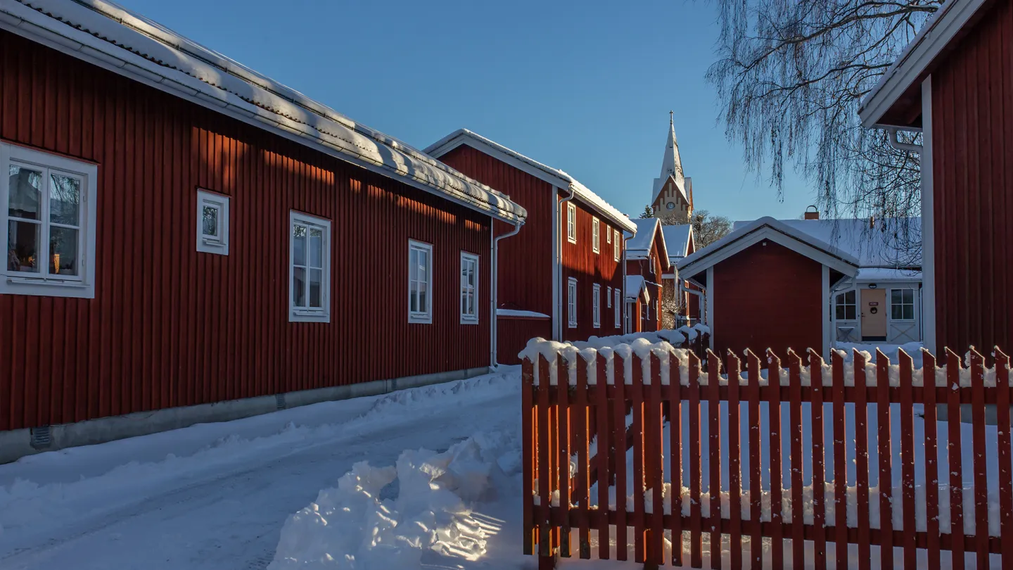 Snöig gata med röda hus i Gamla Byn i Avesta.