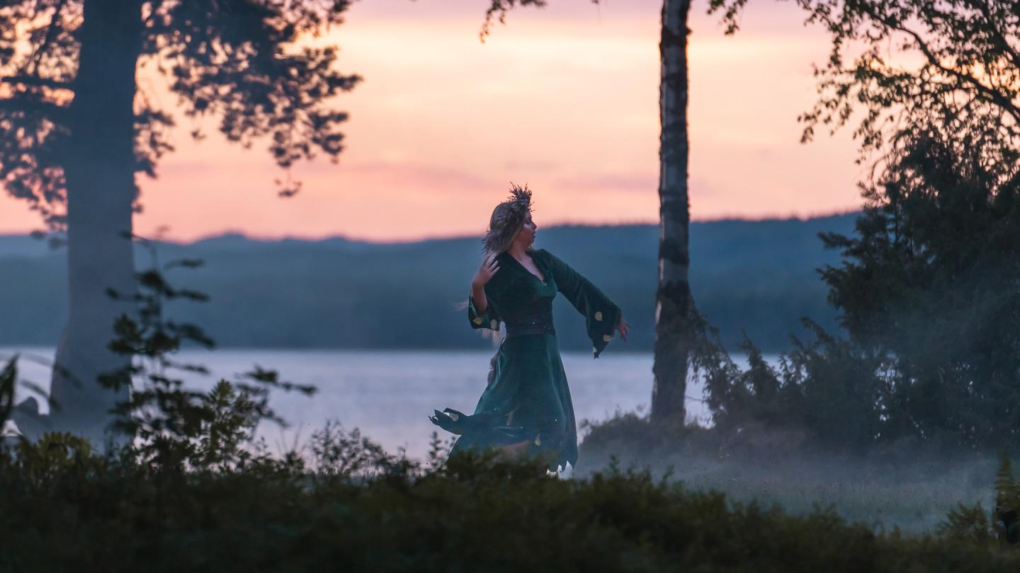 En kvinna dansar i skymning med en sjö i bakgrunden.