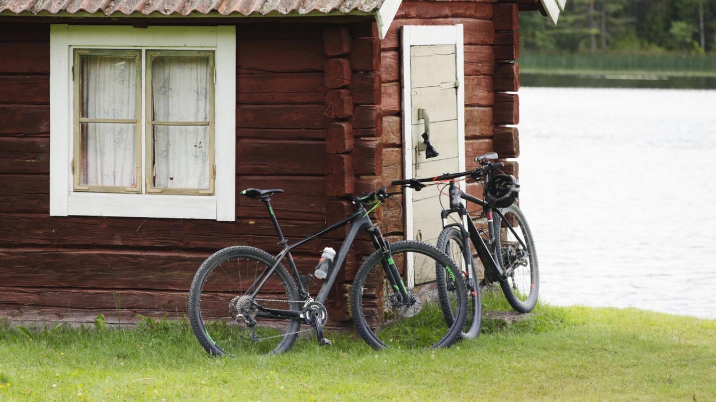 Två cyklar mot husvägg.