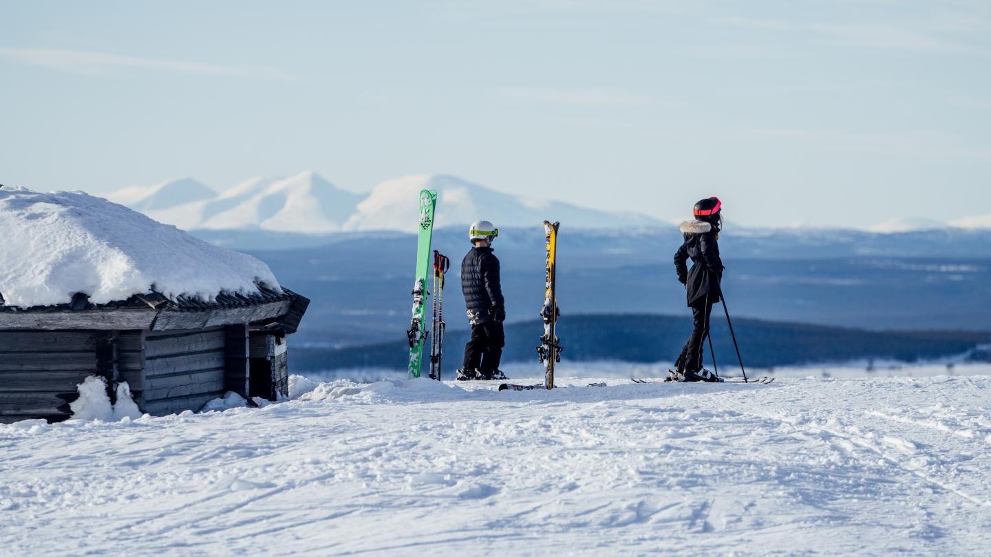 Två personer som står vid sina slalomskidor.
