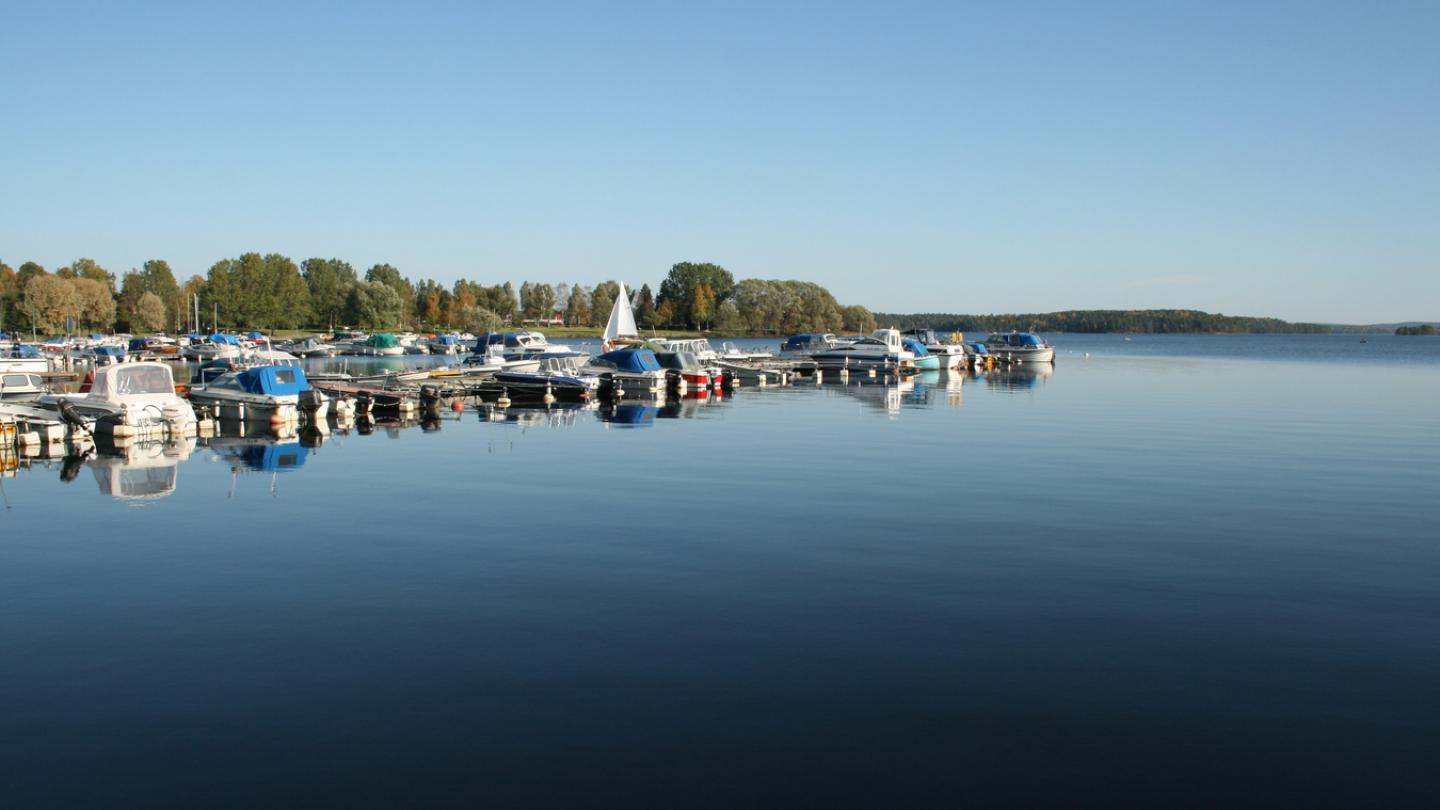 Smedjebackens hamn med båtar, blått vatten och blå himmel.