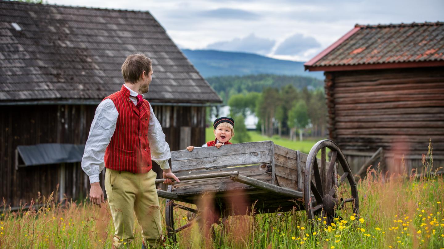 Father and son in folk costume in shack landscape.