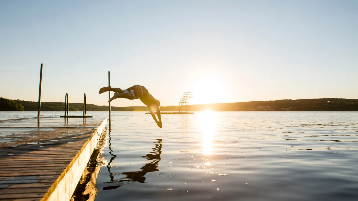 One who dives into the water from the pier at sunset.