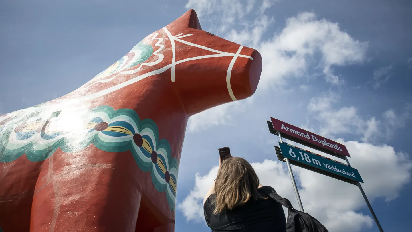 En kvinna fotar en gigantisk dalahäst.