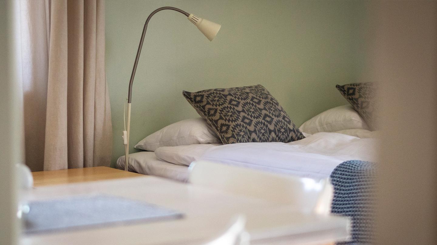 Ett hotellrum med skrivbord, bäddad säng och en sänglampa.