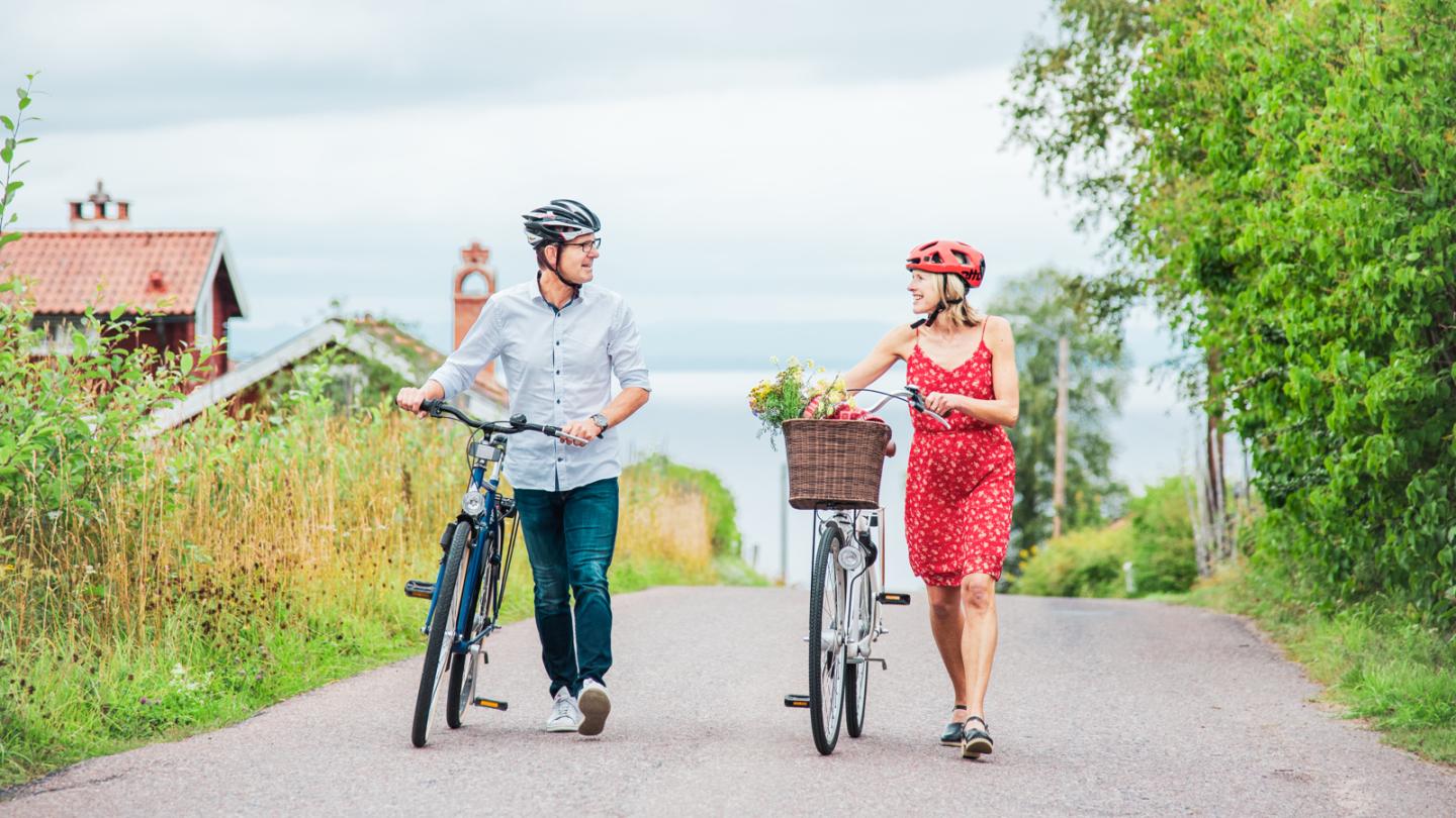 Två personer leder sina cyklar längs väg i Tällberg. 
