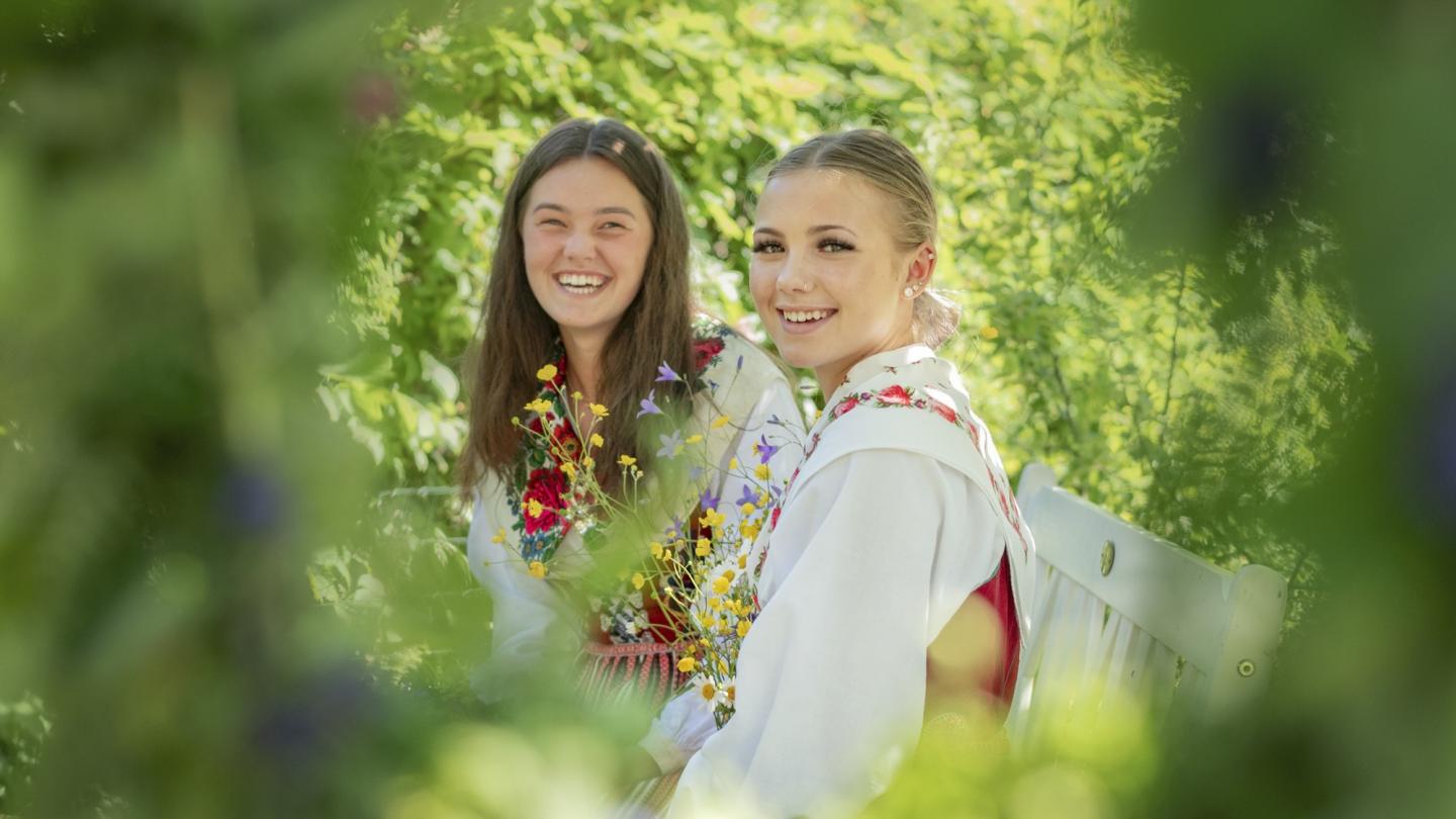 Two girls binding flowers during solstice midsummer.