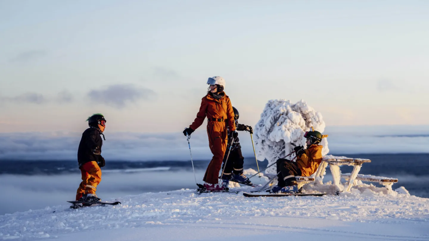 Family on top at the skislope with a clear sky behind them.