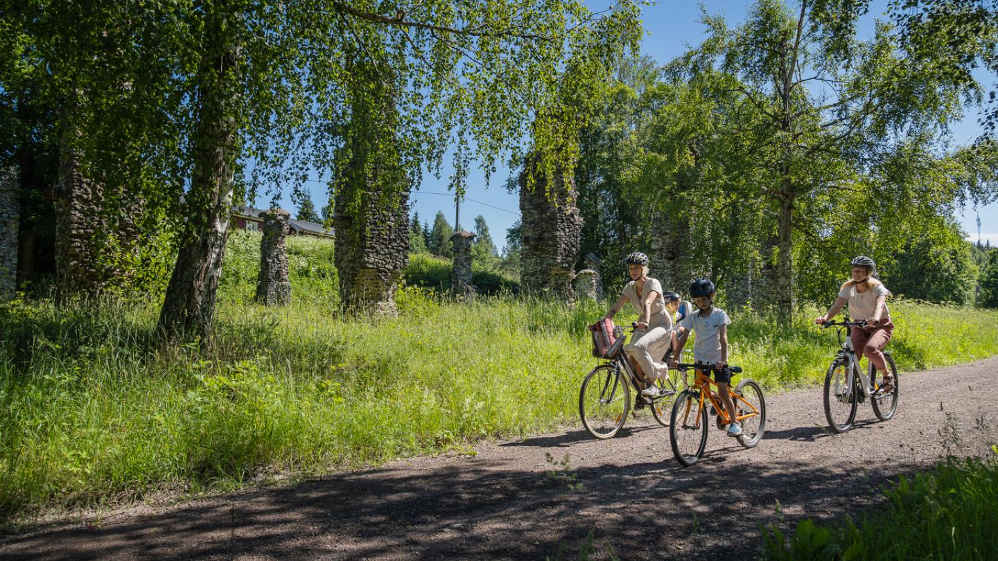 Två kvinnor och två barn på cykel längs en grusväg.