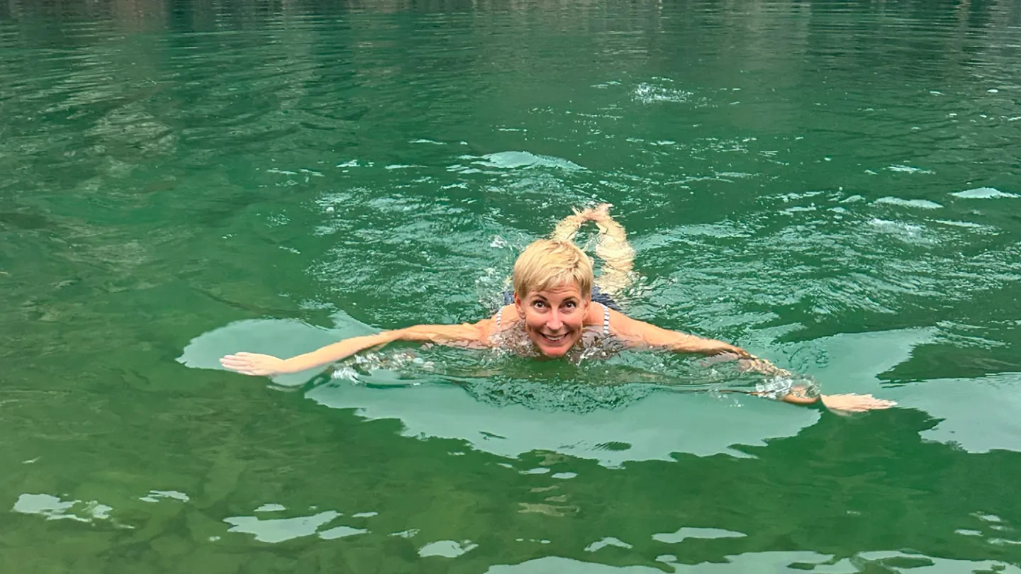 en person som simmar i ett vattendrag.