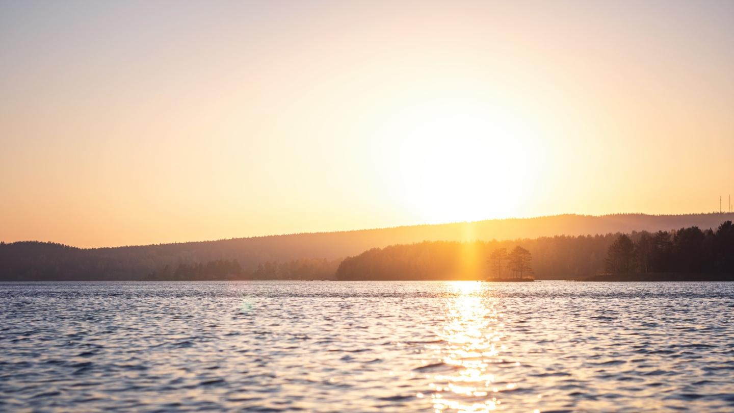Vy över sjö med solnedgång.