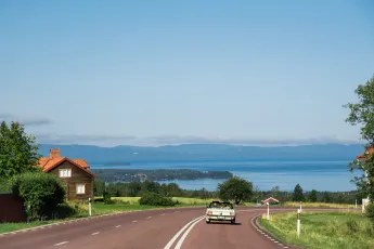 An old veteran car on a road towards a lake.